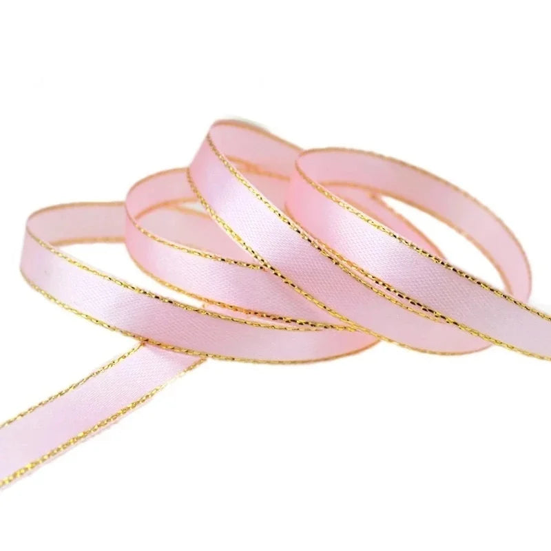 Pink satin ribbon with gold edges rolled into a coil for gift wrapping and crafts