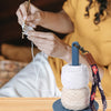A person is using a handheld portable yarn holder to wind and manage yarn for knitting.