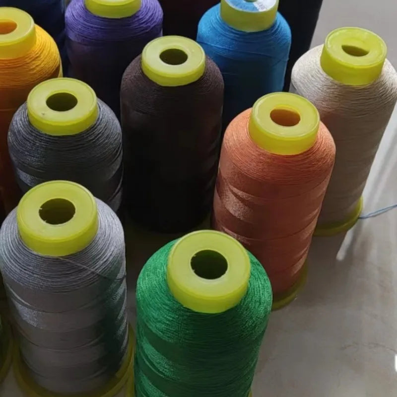 A collection of spools of high tenacity polyester sewing thread in various colors including purple, brown, teal, orange, and 