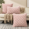 A collection of pink and beige textured plush pillows and throws displayed on a light-colored sofa.