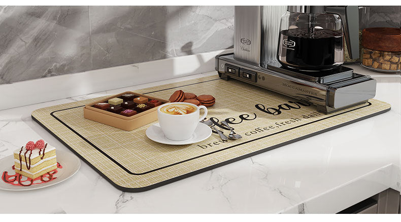 A wooden mat with coffee beans and treats is placed on a white marble countertop next to an espresso machine.