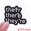 Black embroidered patches with white text spelling out the phrase they are