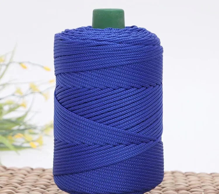 A spool of deep blue crochet ice rope with a green cap resting on a woven mat.