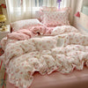 Pink floral bedding set with ruffled duvet and pillows displayed on a bed.