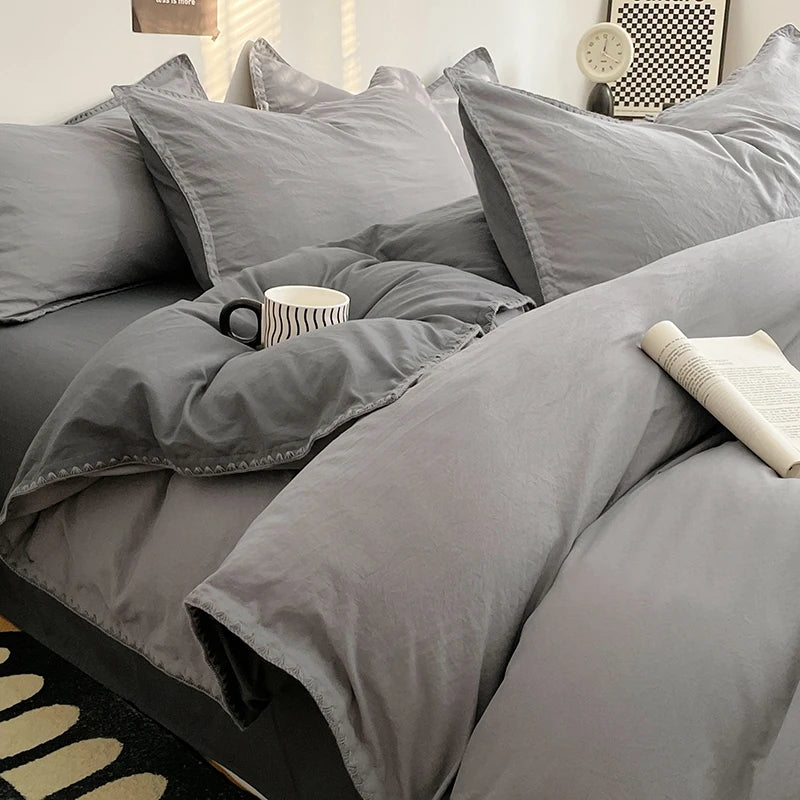 A close-up of a gray luxurious washed cotton bed linen set featuring pillows and a folded blanket on a bed.