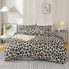 A leopard print duvet cover set featuring black and beige spots on a bed with a light gray rug.