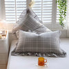A set of two soft plaid washed cotton pillowcases with ruffled edges resting on a white surface.