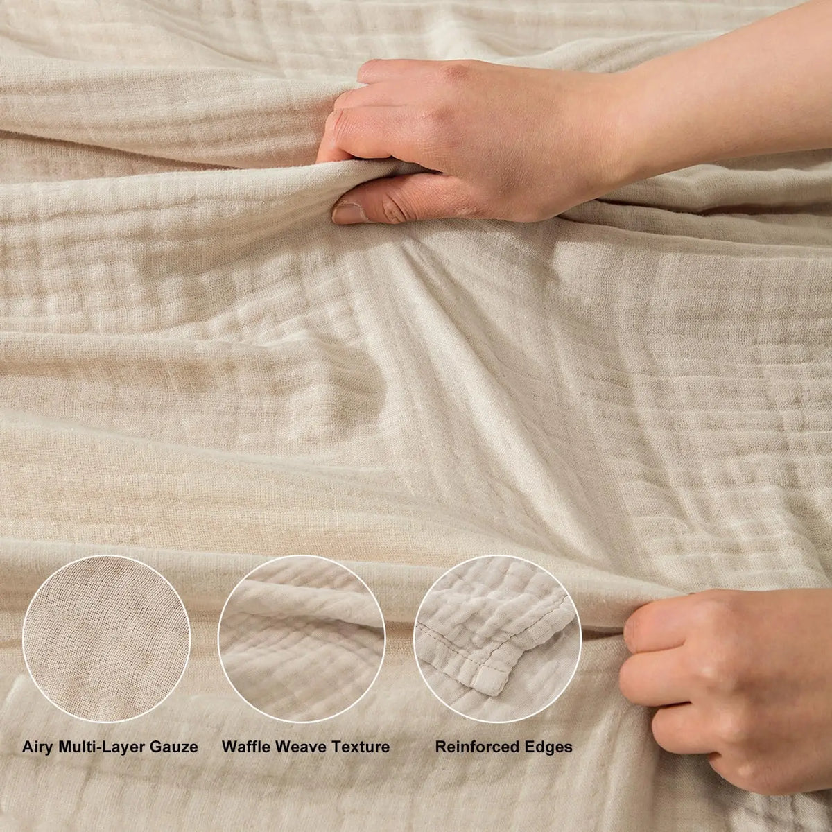 Close-up of a beige muslin blanket showing multi-layer gauze texture and reinforced edges being held by hands.
