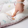 A hand is pressing into a white fiber pillow featuring cartoon fish and other animals.