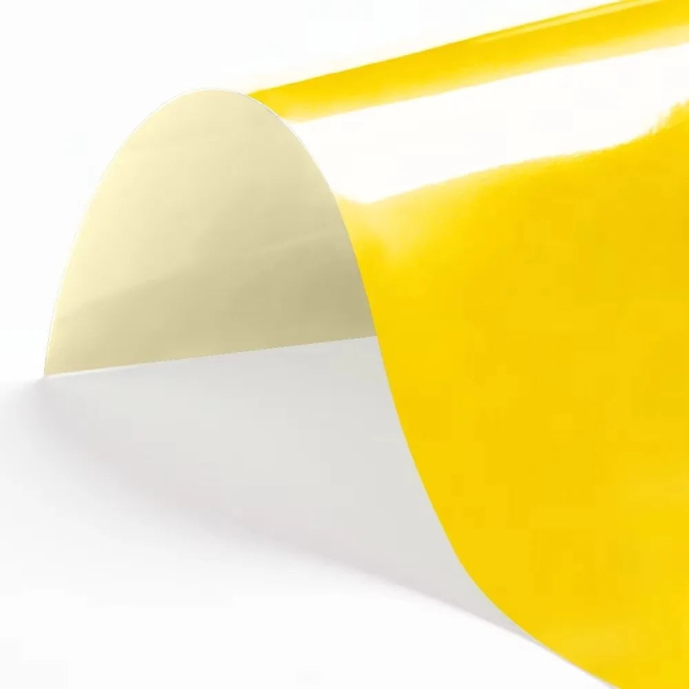 A sheet of yellow heat transfer vinyl being peeled off a white backing.