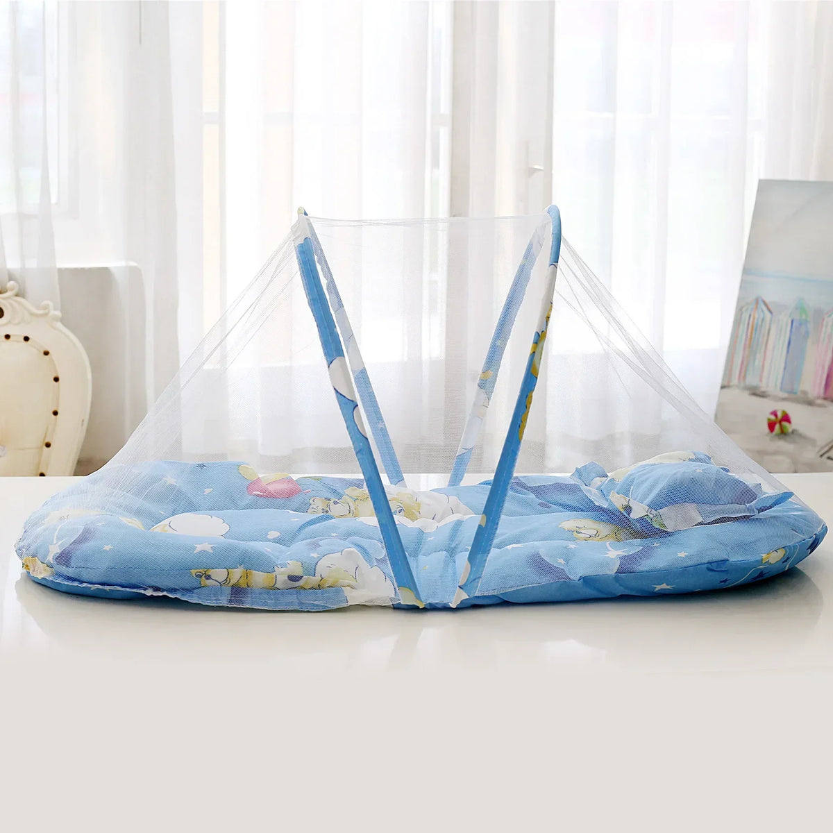 A portable baby crib net with soft blue and yellow padding is displayed on a white surface.