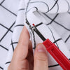 A hand uses a red seam ripper tool to separate fabric layers on a white and black checkered cloth.