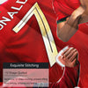 Close-up of a red soccer jersey fabric with gold stitching detail on a person's arm.