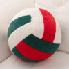 A plush volleyball ball cushion with a white and red striped pattern.