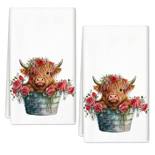 A kitchen towel featuring a watercolor illustration of a brown Highland cow with horns surrounded by pink and red roses in a 
