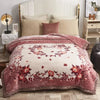 A beige weighted blanket with a pink floral pattern is displayed on a bed with white linens and a light wood nightstand.
