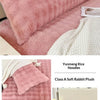 Pink plush long pillowcases and a white textured blanket displayed on a bed.
