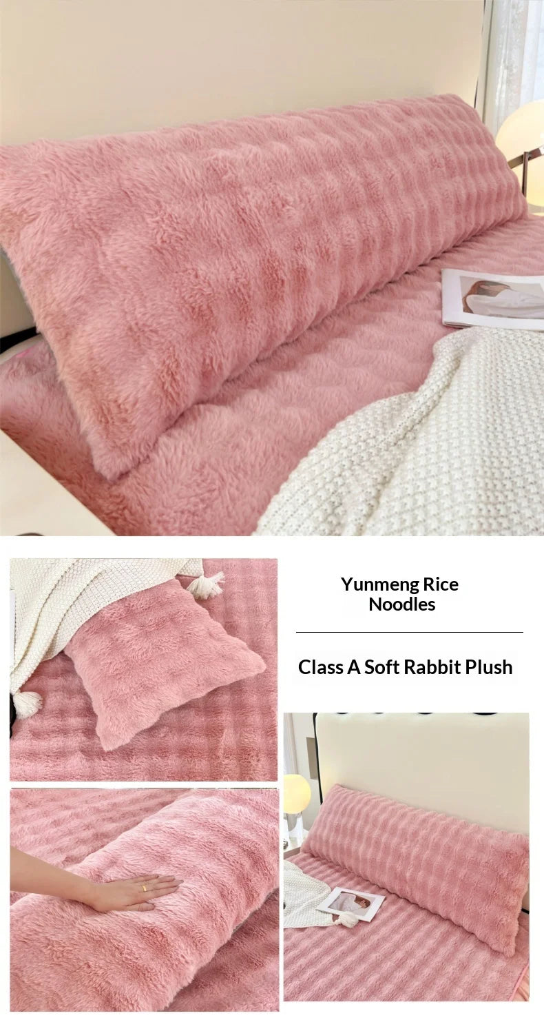 Pink plush long pillowcases and a white textured blanket displayed on a bed.