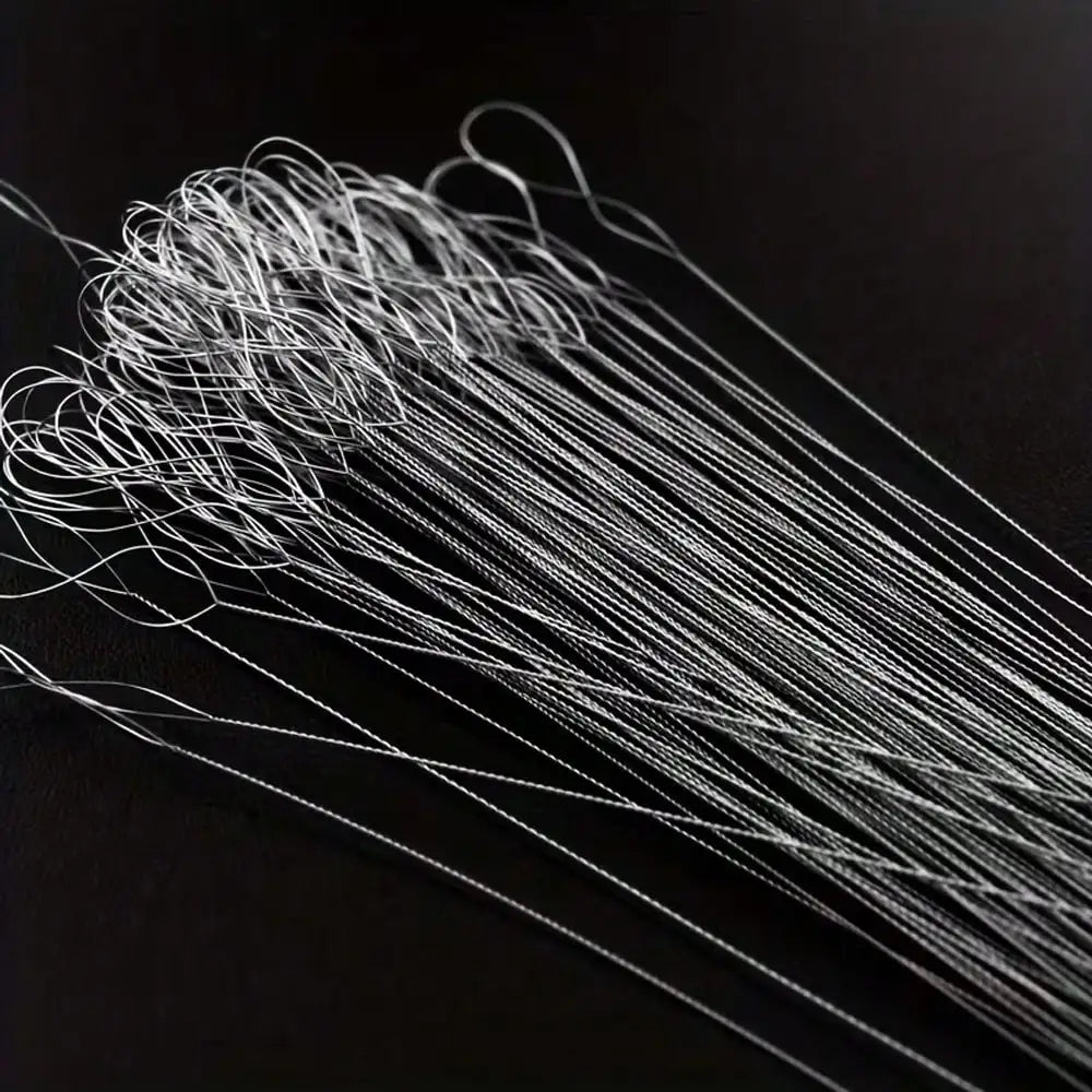 A bundle of thin, silver-colored beading needles laid out on a dark surface.
