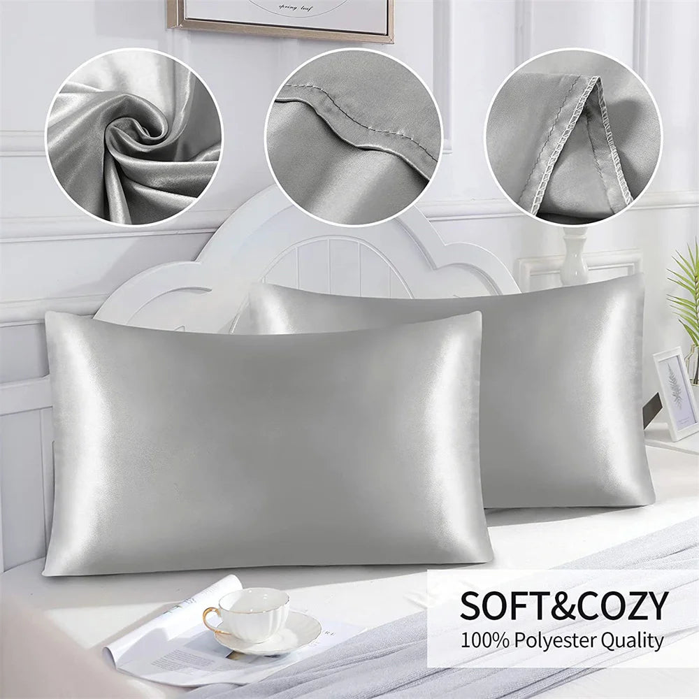 A silver satin pillowcase is displayed next to a white wooden headboard and a cup, highlighting its soft and cozy texture.