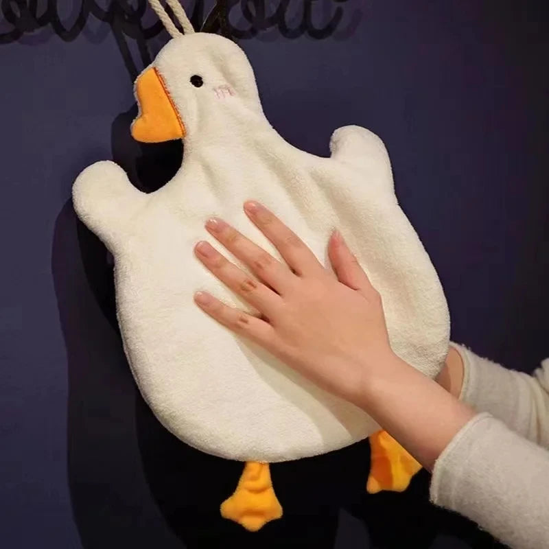 A hand is holding a white cartoon goose hanging towel with orange feet against a dark background.