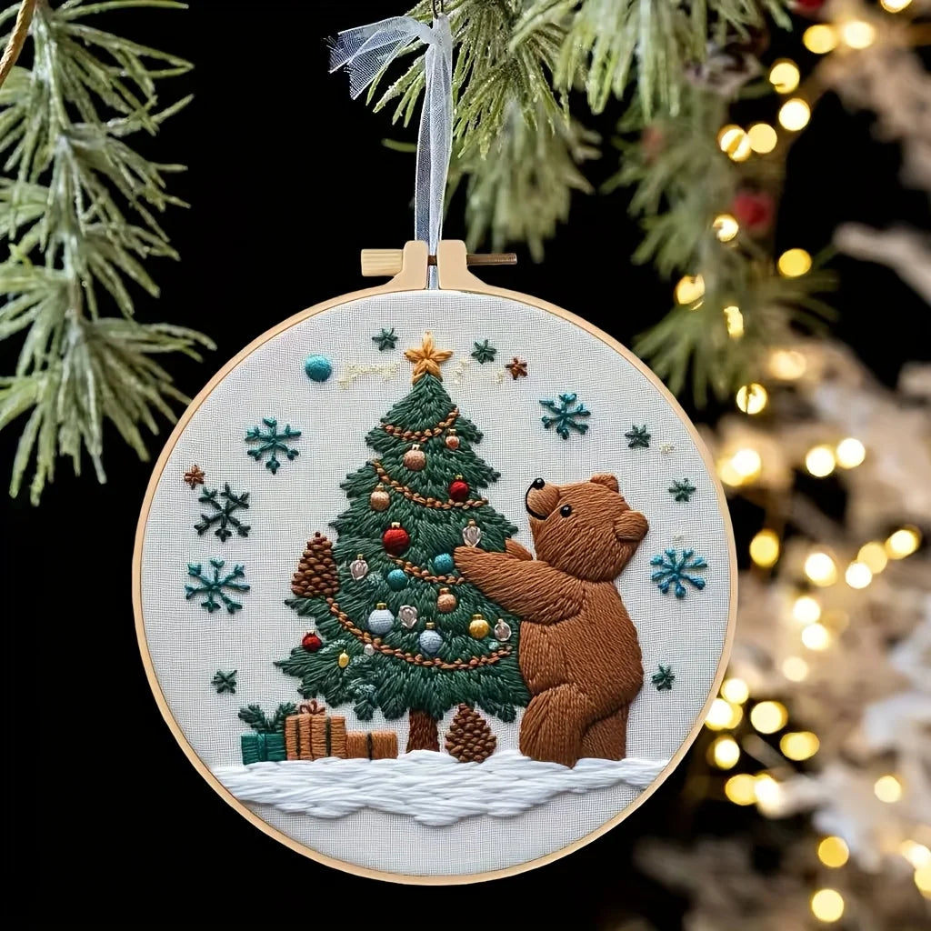A hand embroidery kit featuring a stitched Christmas tree with ornaments and a bear figure on a white background.