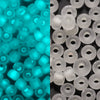 A close-up view of small, translucent blue glow-in-the-dark glass seed beads and white glass beads.