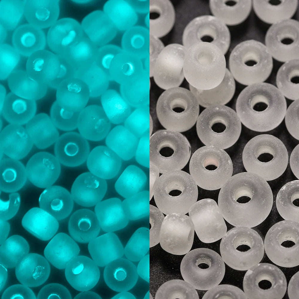 A close-up view of small, translucent blue glow-in-the-dark glass seed beads and white glass beads.