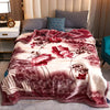 A plush mink fleece king size blanket featuring a floral pattern in shades of rose and peony on a gray sofa.