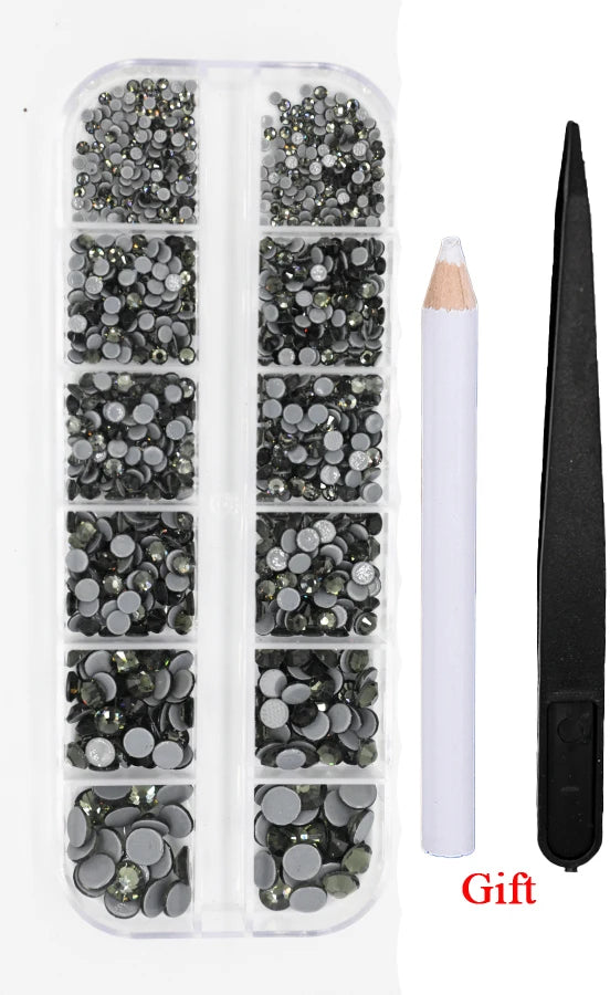 A clear plastic container holds various sizes of dark and silver crystal hot fix rhinestones and an applicator tool.