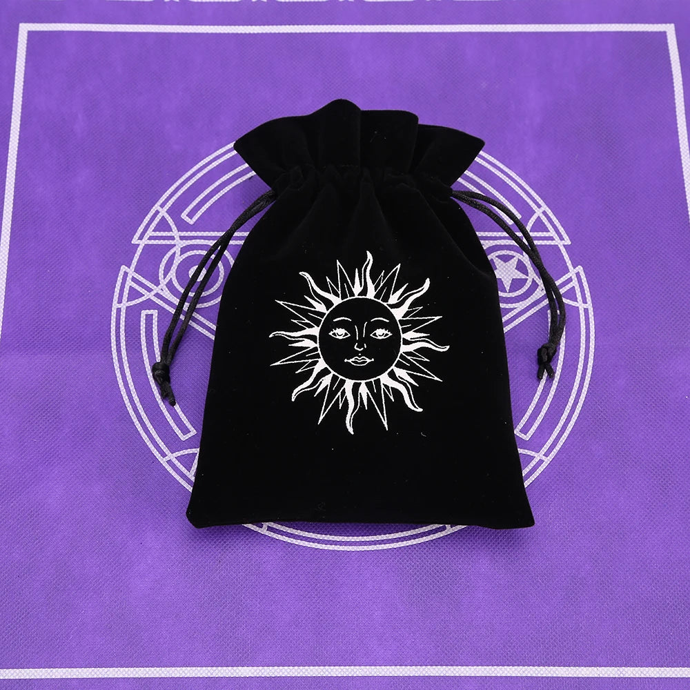 A black velvet pouch with a white sun symbol is displayed on a purple cloth background.