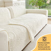 A cream colored sofa cushion with a textured pattern shown on a light-colored sofa.