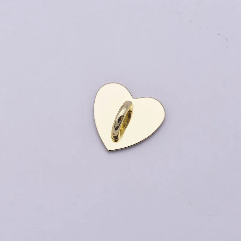 A small, polished gold-colored metal heart charm with a cylindrical connector attached.