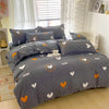 A gray and white patterned duvet cover set with two pillows featuring orange and white heart designs.