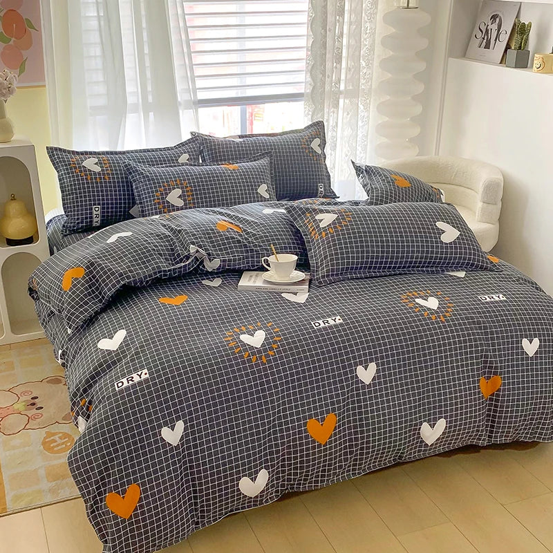 A gray and white patterned duvet cover set with two pillows featuring orange and white heart designs.