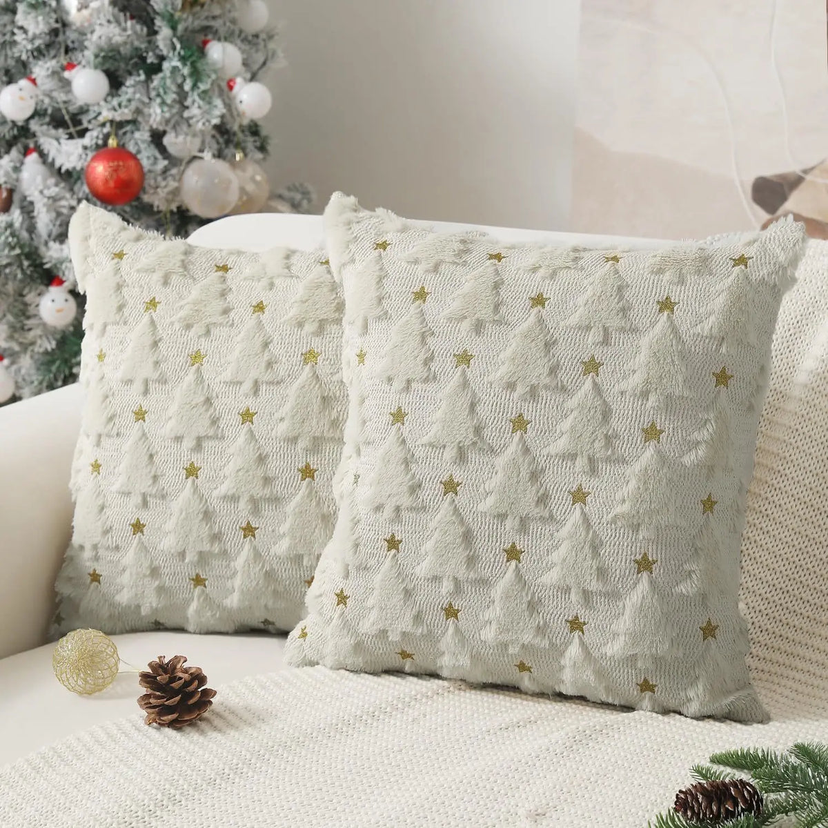 Two light cream knitted cushion covers with a repeating star pattern resting on a white sofa.