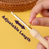 A hand is adjusting the length of a silver punch needle tool with a wooden handle.