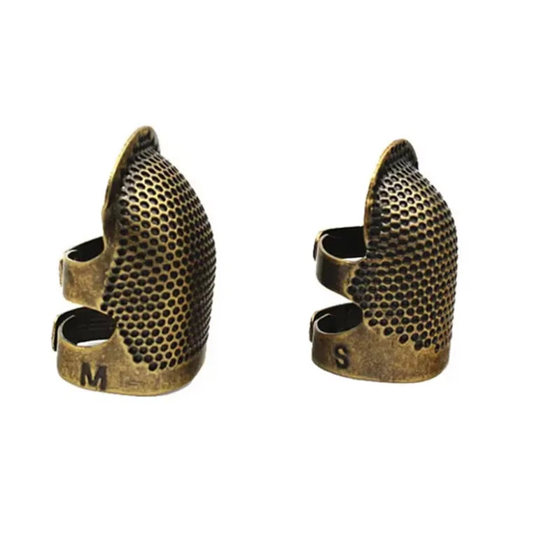 A pair of antique sewing thimbles and needle protectors, one marked M and the other S, made of brass or bronze.