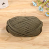 A ball of olive green flat thread yarn for crafting and sewing resting on a wooden surface.
