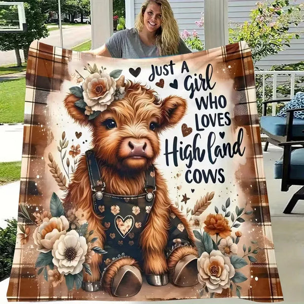 A close-up illustration of a Highland cow wearing a leather harness surrounded by flowers and foliage on a brown flannel blan