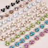 A collection of flower-shaped resin button rhinestones in various shades of pink, white, green, and blue.