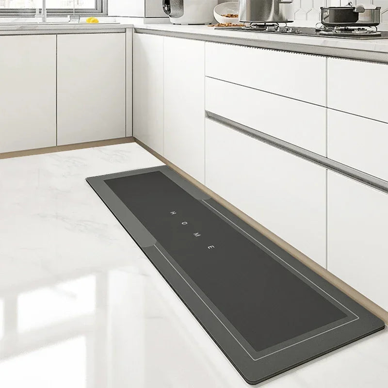 A black anti-slip floor mat is placed on a white kitchen floor next to white cabinets.