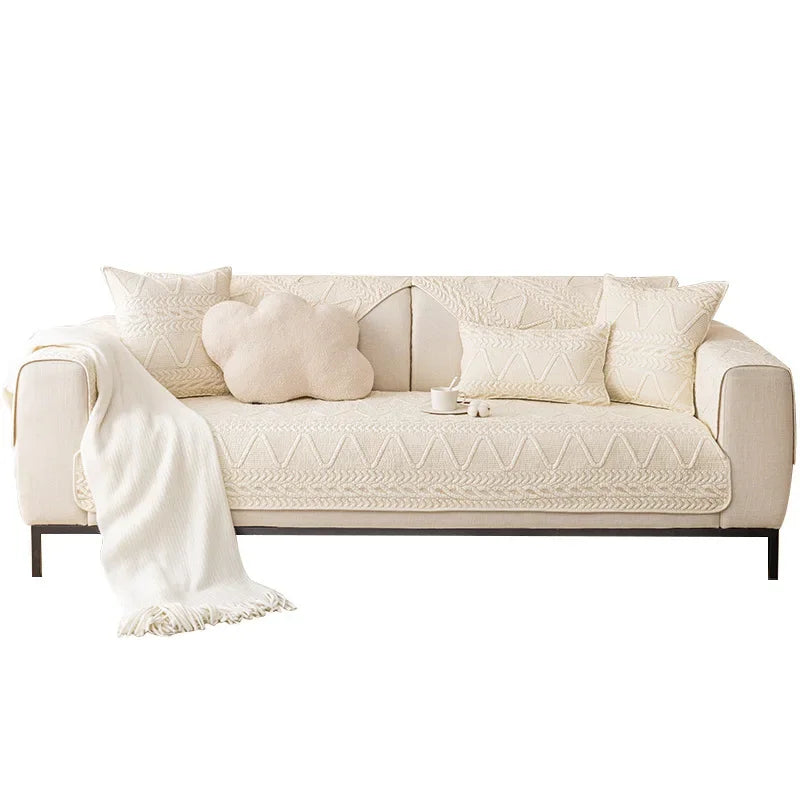 A cream colored sofa cover featuring a textured weave and several matching throw pillows.