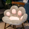 A soft gray plush bear paw cushion resting on a wooden chair.