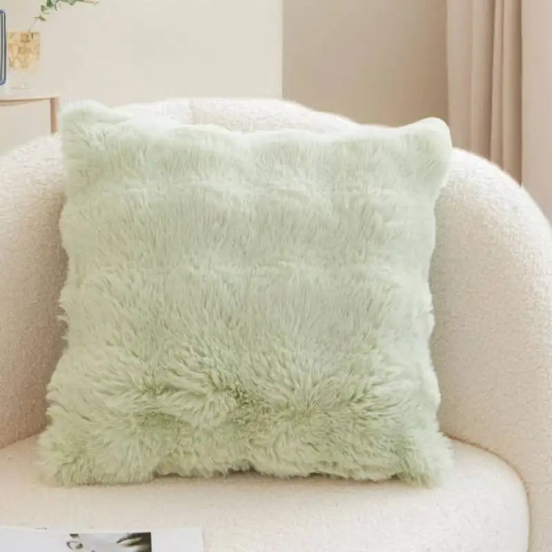 A light mint green plush faux rabbit fur decorative throw pillow resting on a cream-colored sofa.