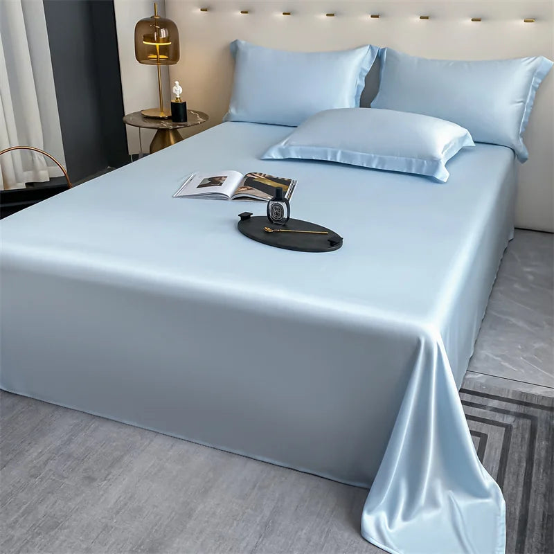 Light blue luxury bamboo flat sheets displayed on a bed with matching pillows and a book.