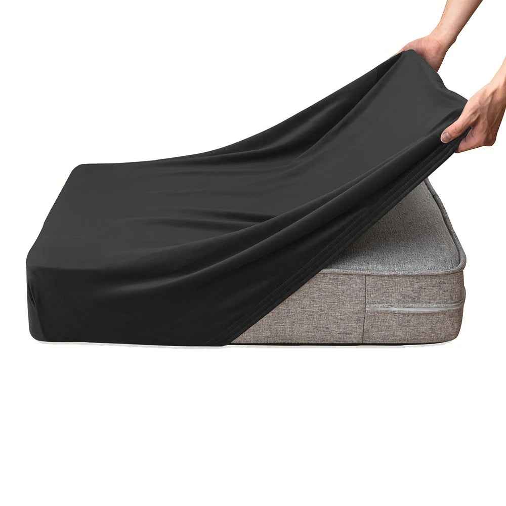 A hand is draping a black velvet stretchy sofa seat cover over a gray sofa cushion.