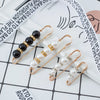Gold-toned adjustable pearl brooches displayed on a white background with a spiral notebook.