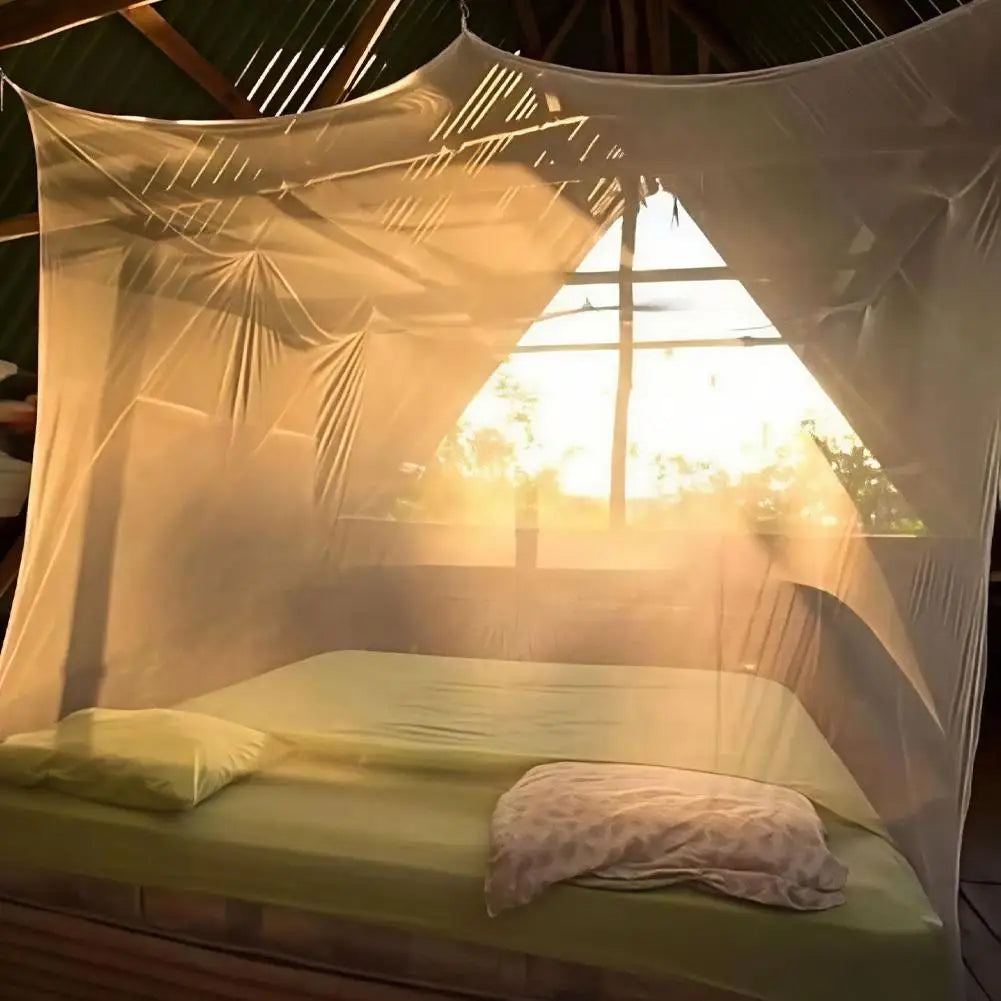 A sheer white mosquito net draped over a bed inside a tent or gazebo, letting in bright sunlight.