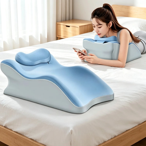 A young woman is lying on a bed using a light blue ergonomic wedge pillow for support while looking at her phone.